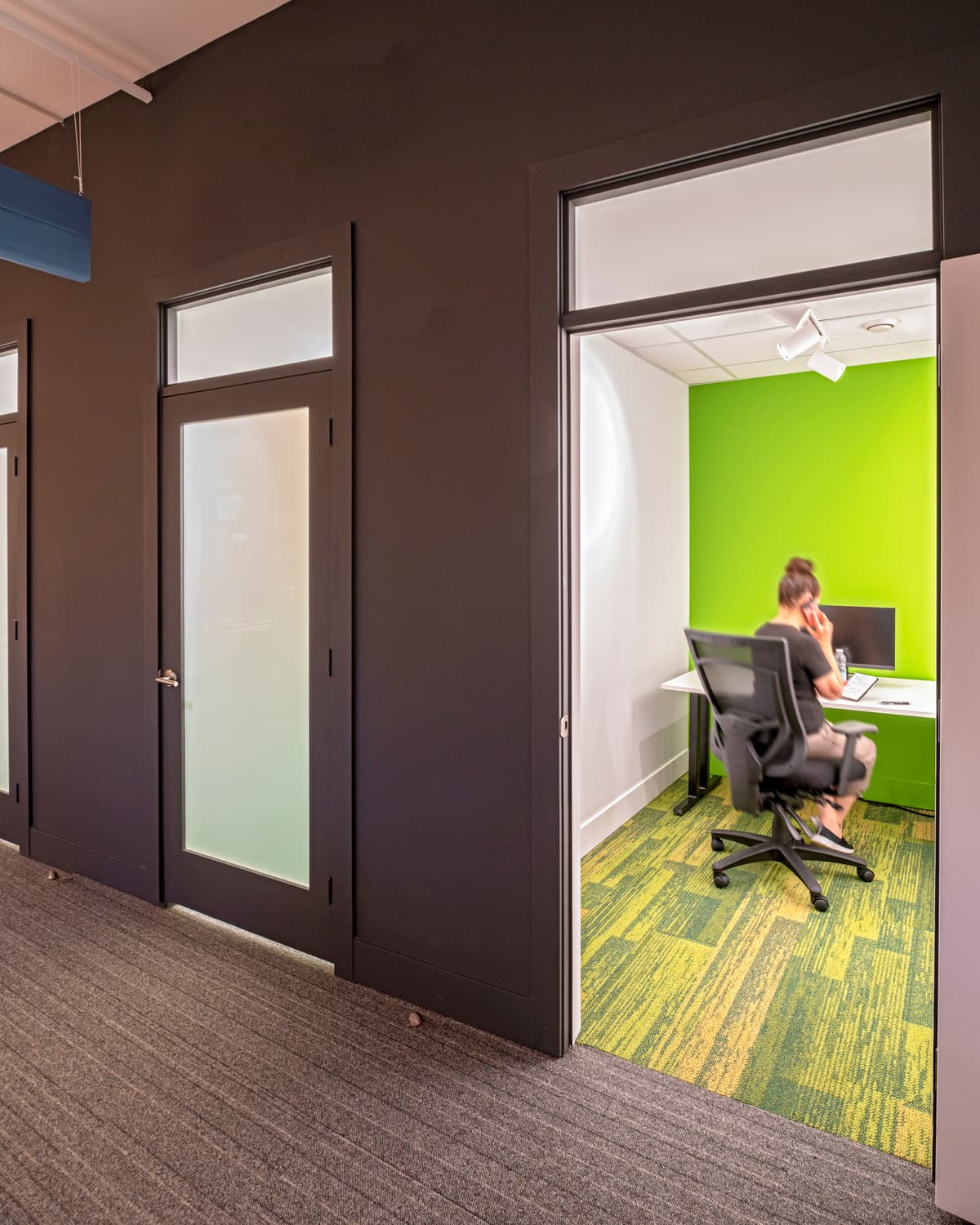 A glazed private room opens from the shared office circulation.