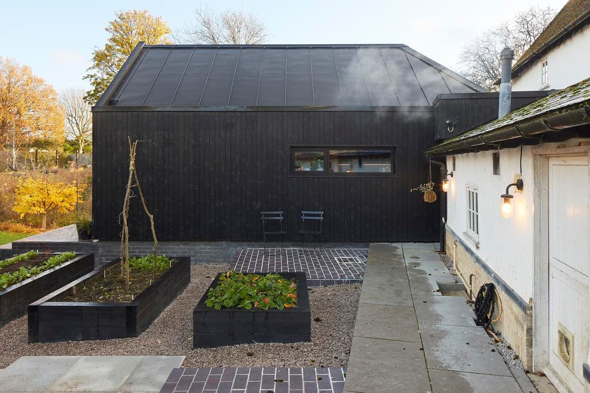 Dark vertical timber cladding meets the courtyard and the existing house.