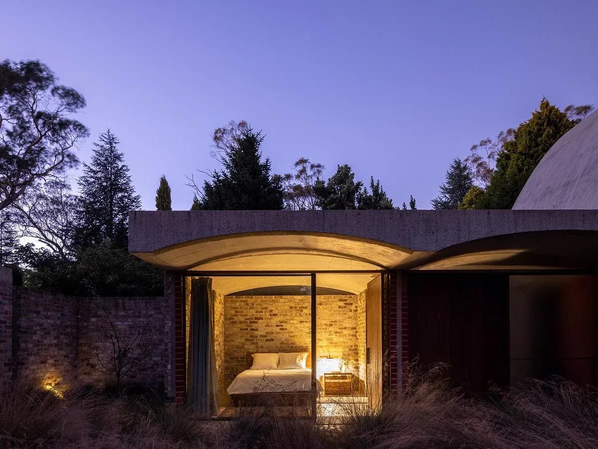 Warm interior light reaches the courtyard at dusk.