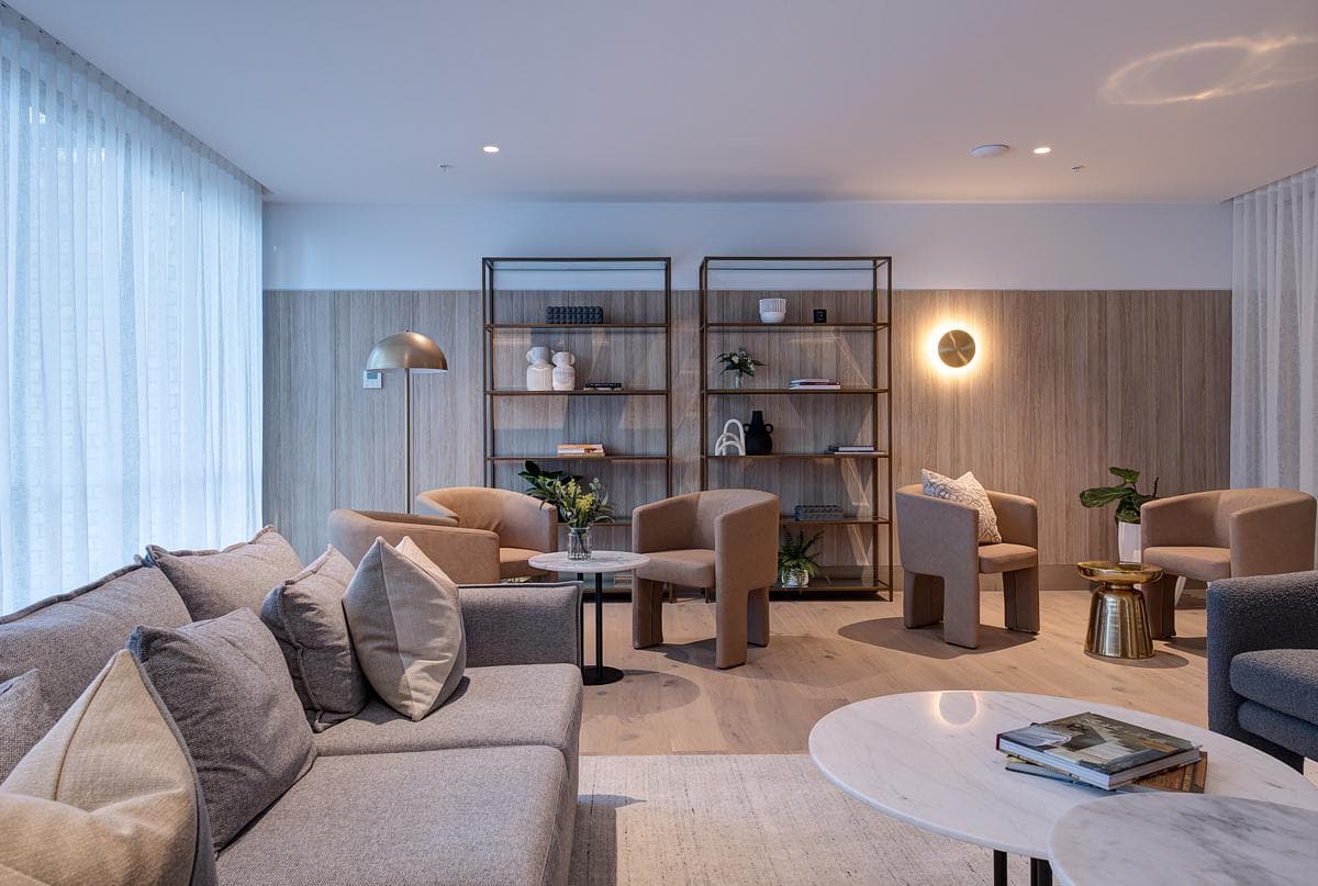 A shared lounge combines seating, shelving and soft window light.