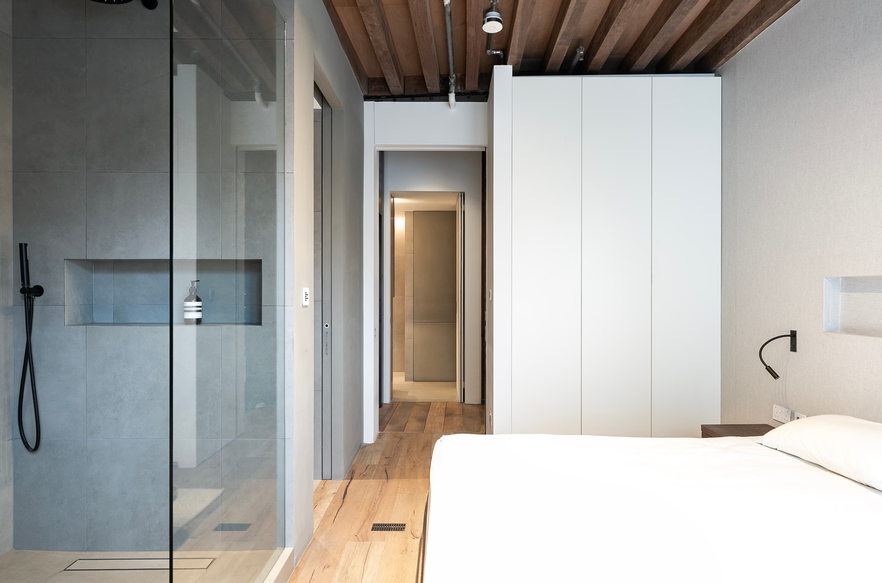 White joinery and a glazed screen organise the bedroom and bathroom.