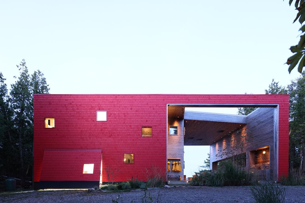 Red shingles frame a large sheltered opening beside the house.