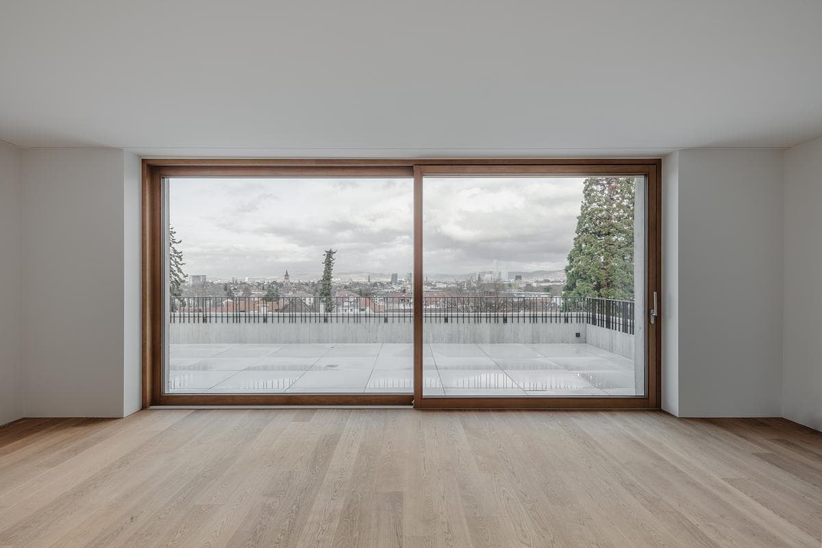 A broad timber-framed window opens the apartment towards the city