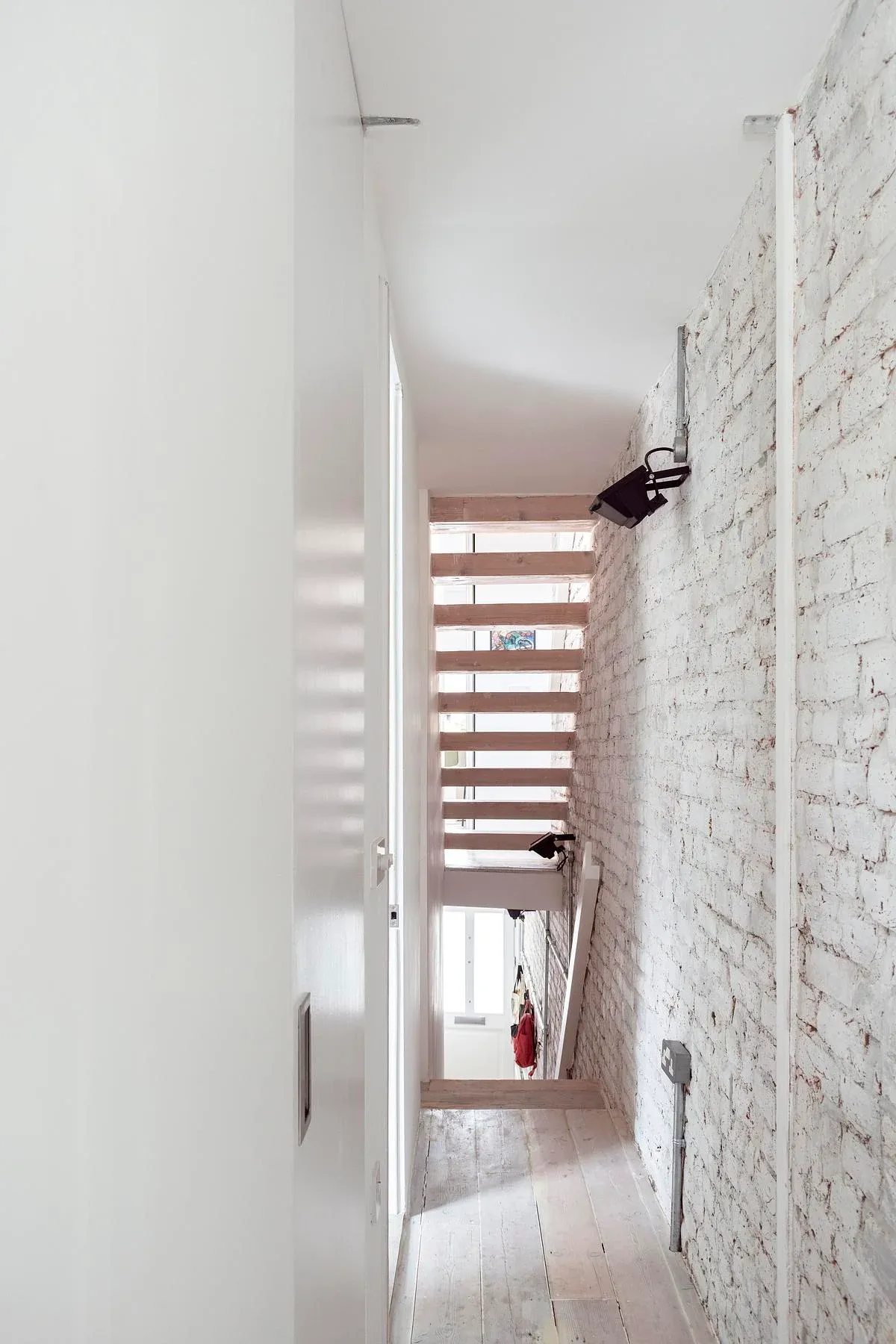 An exposed brick wall and concealed doors shape the hallway.