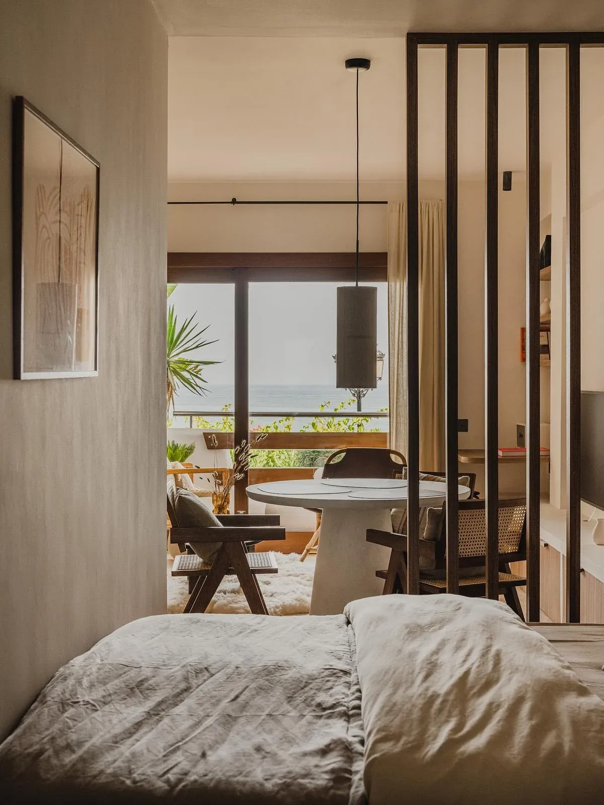 The bed faces the living area through a timber slatted divider.