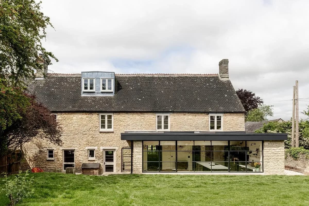 The low steel-framed extension sits at the back of the Cotswold stone cottage.