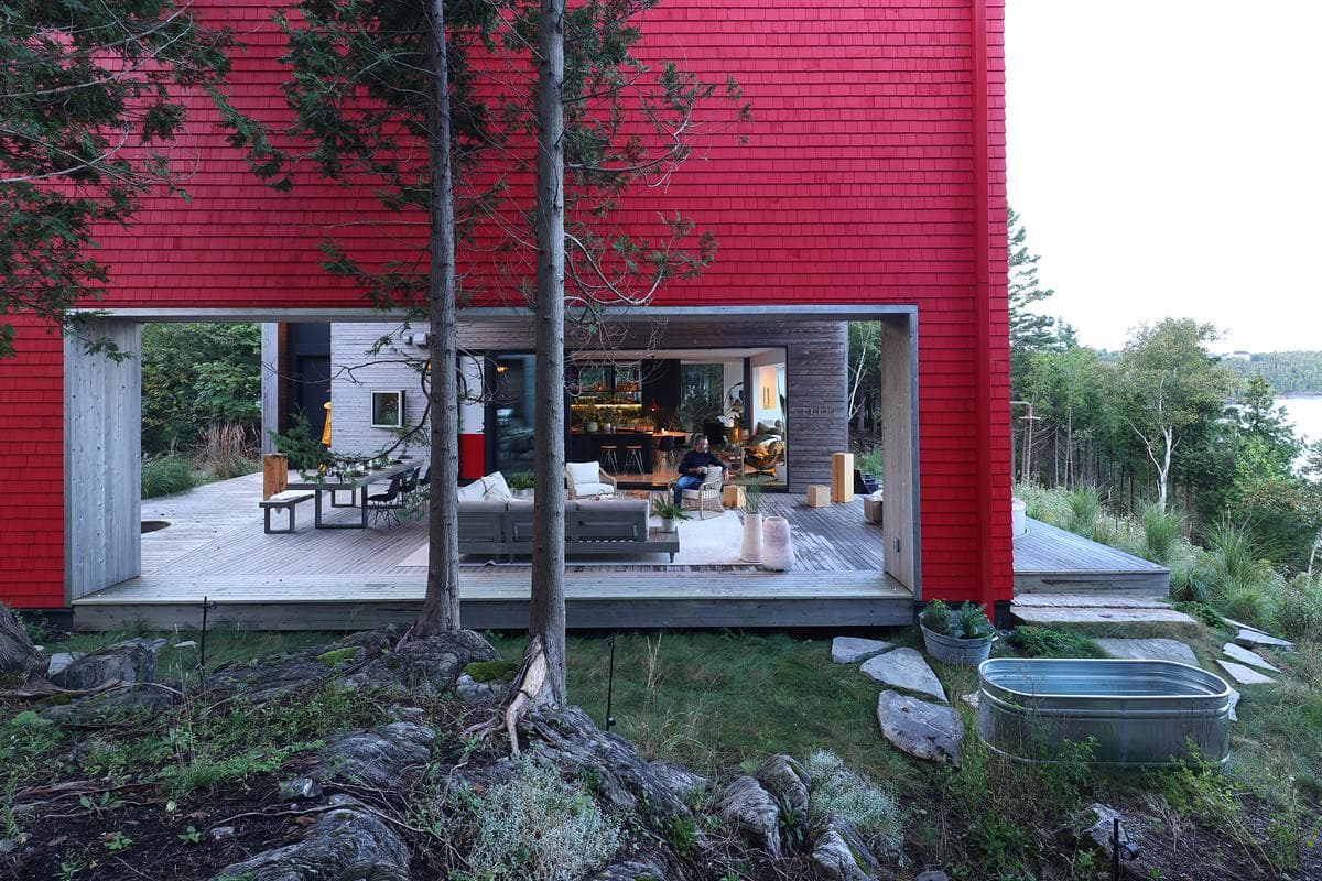 The living space opens onto a timber deck and outdoor seating.