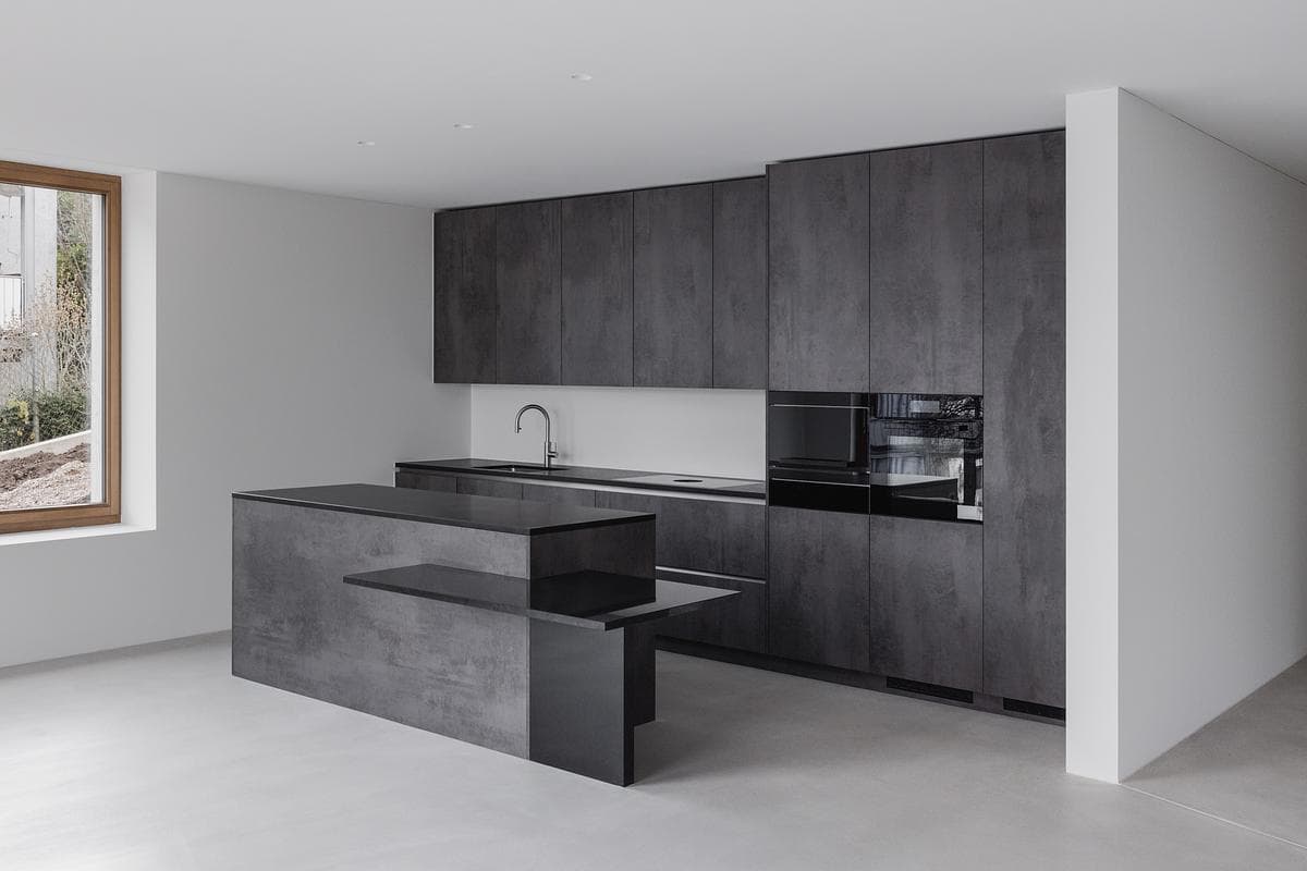 A dark kitchen island and splashback contrast with the pale room.