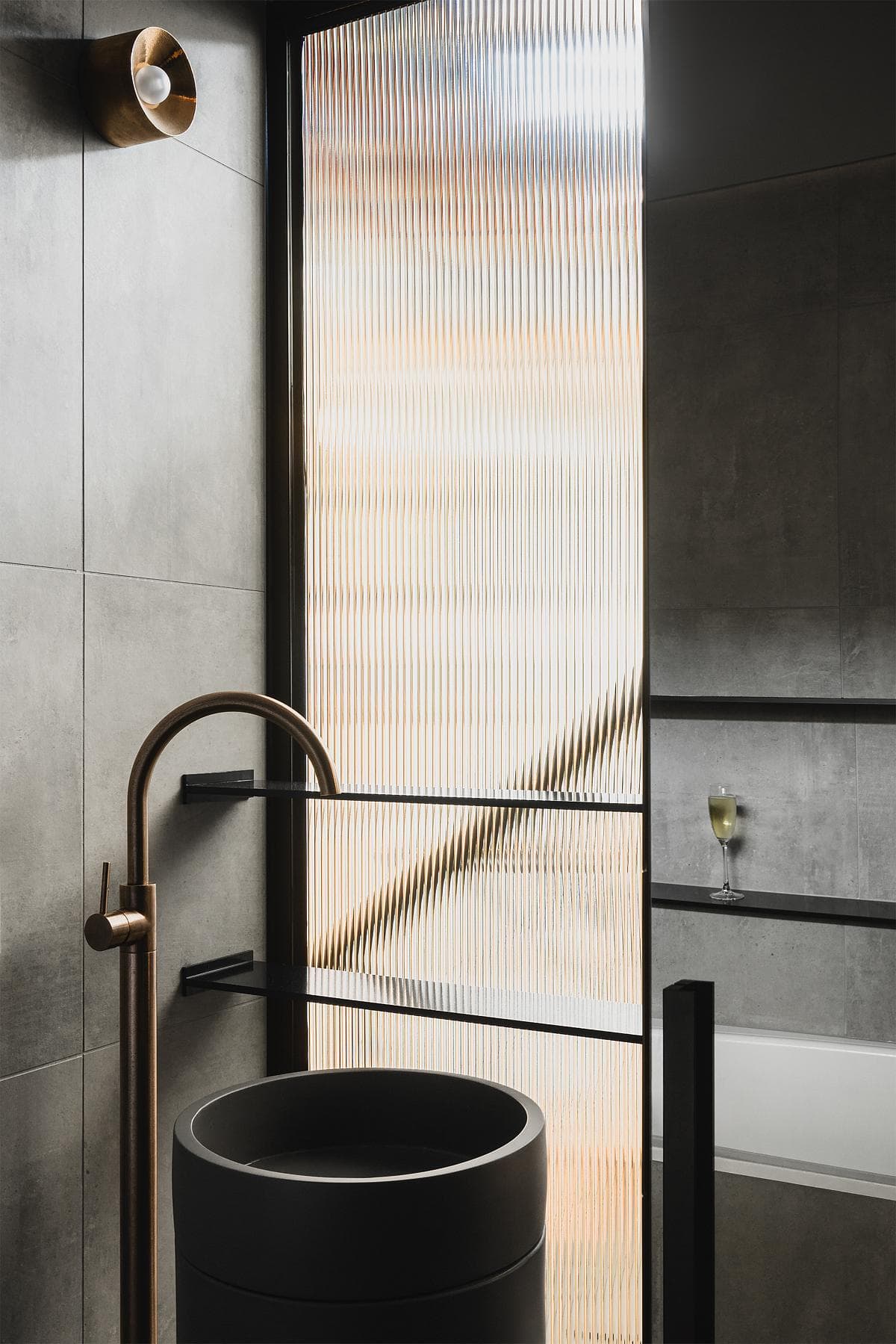 A compact basin and metal fittings sit against a textured wall.