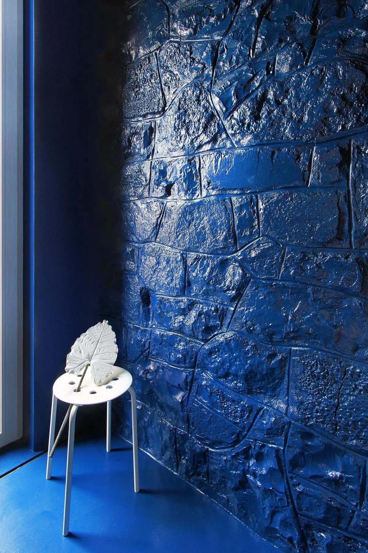 Blue resin wraps the bathroom beside an exposed stone wall.