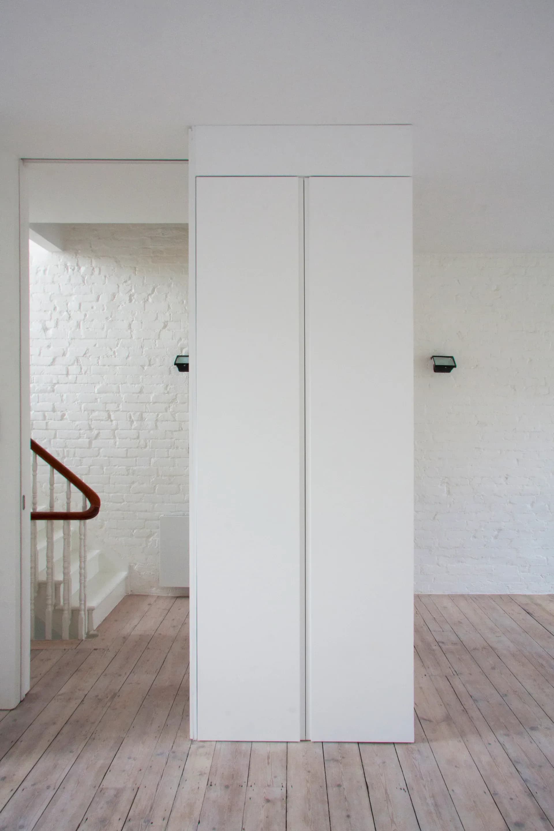 A freestanding white volume divides the room without closing off the floor.