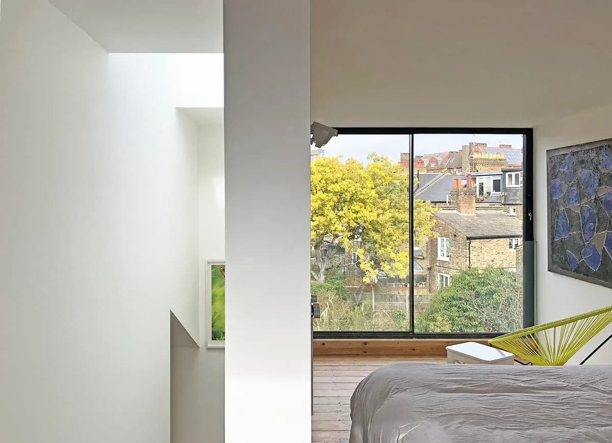Full-height glazing opens the roof-level bedroom towards the surrounding rooftops.