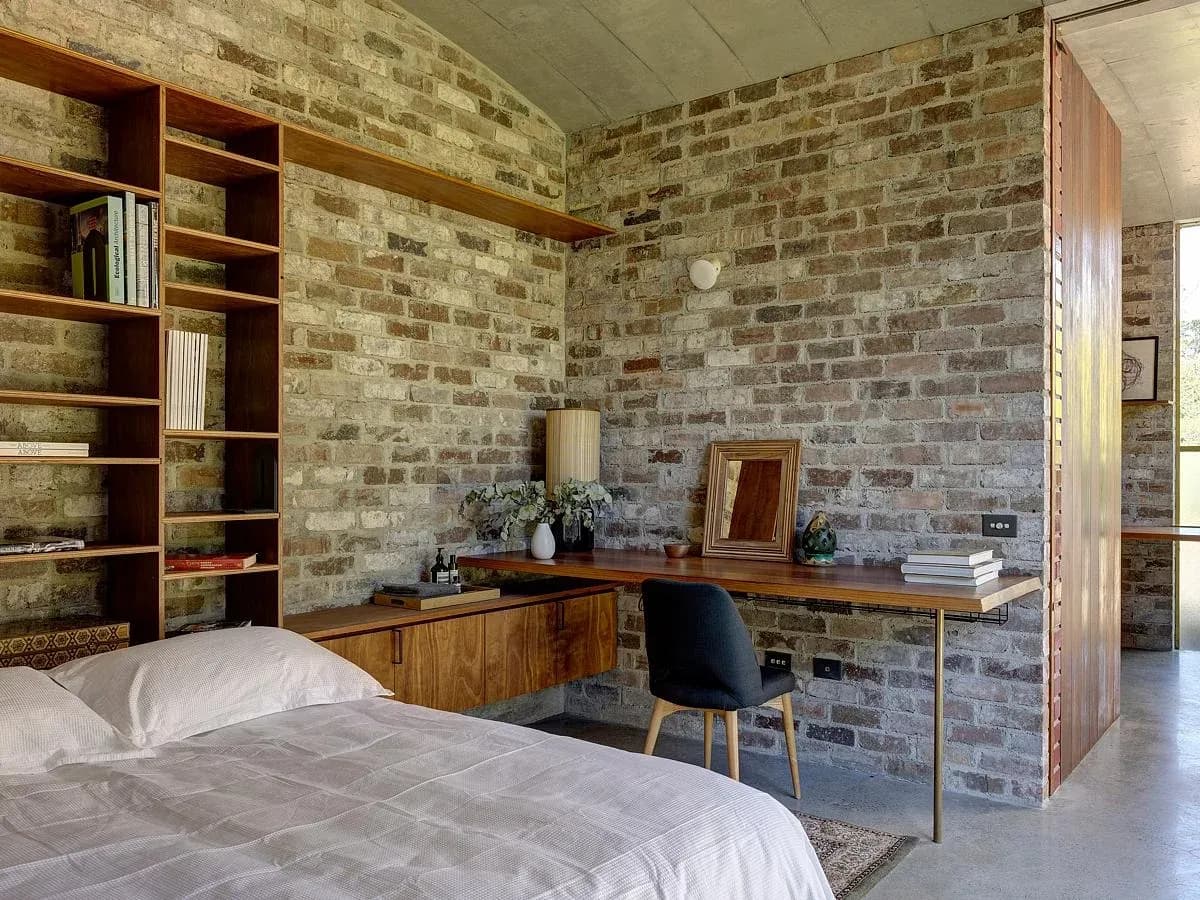 A bedroom with fitted timber shelving opens towards the garden.