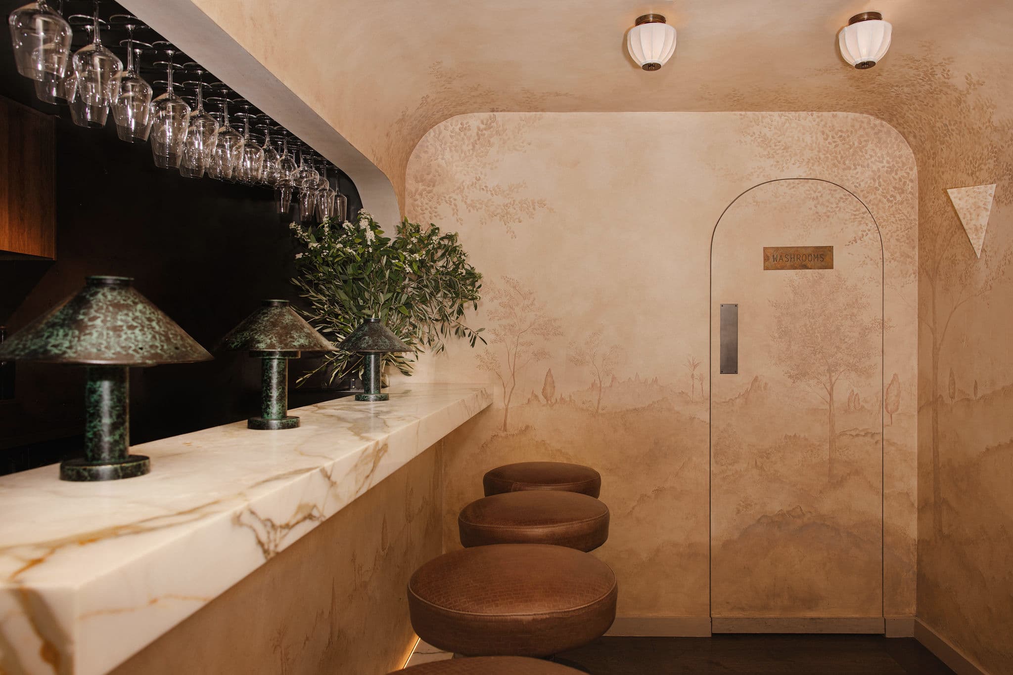 The basement bar pairs marble with a hand-painted mural.