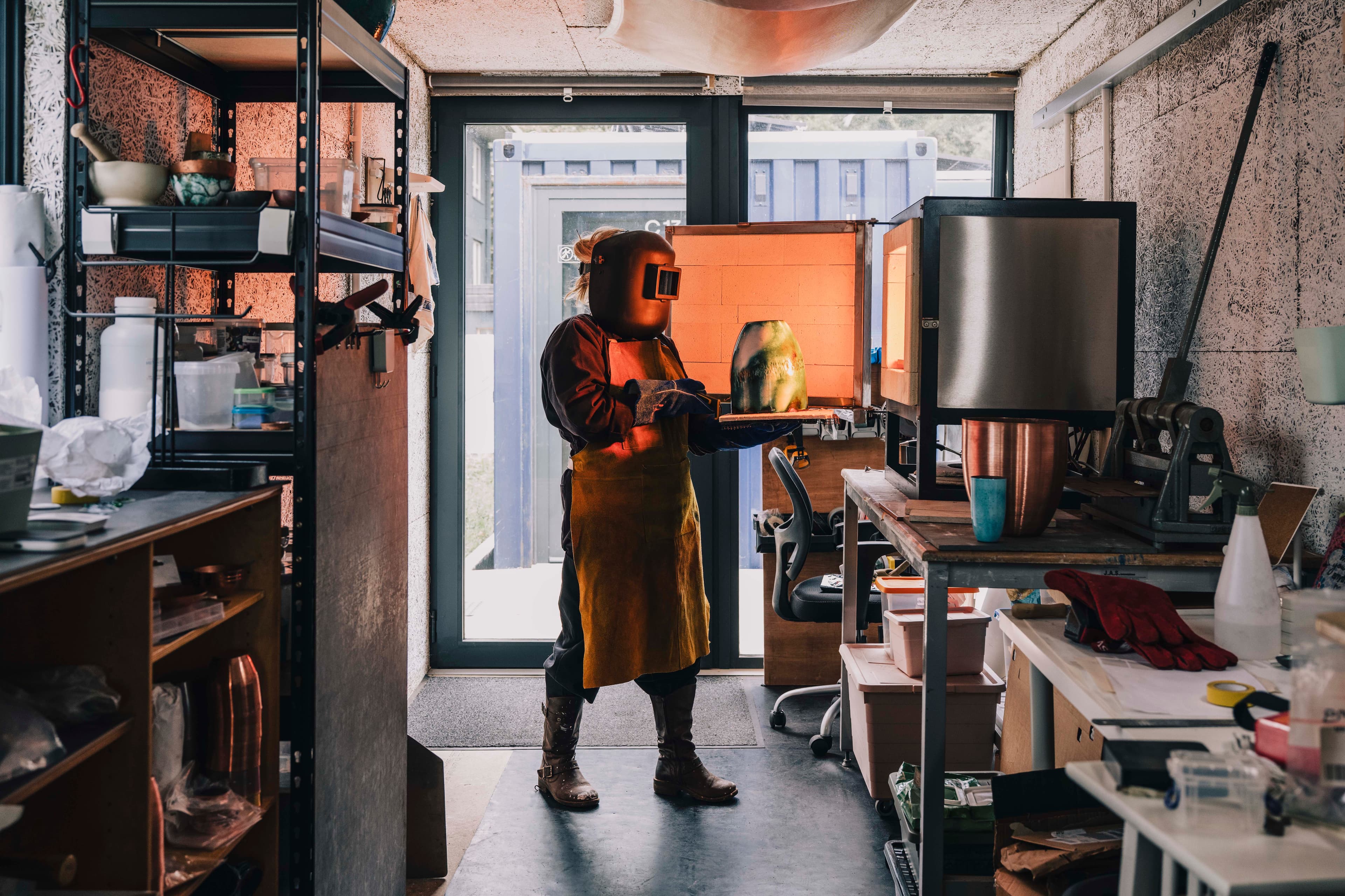 An artist at work inside a container studio.