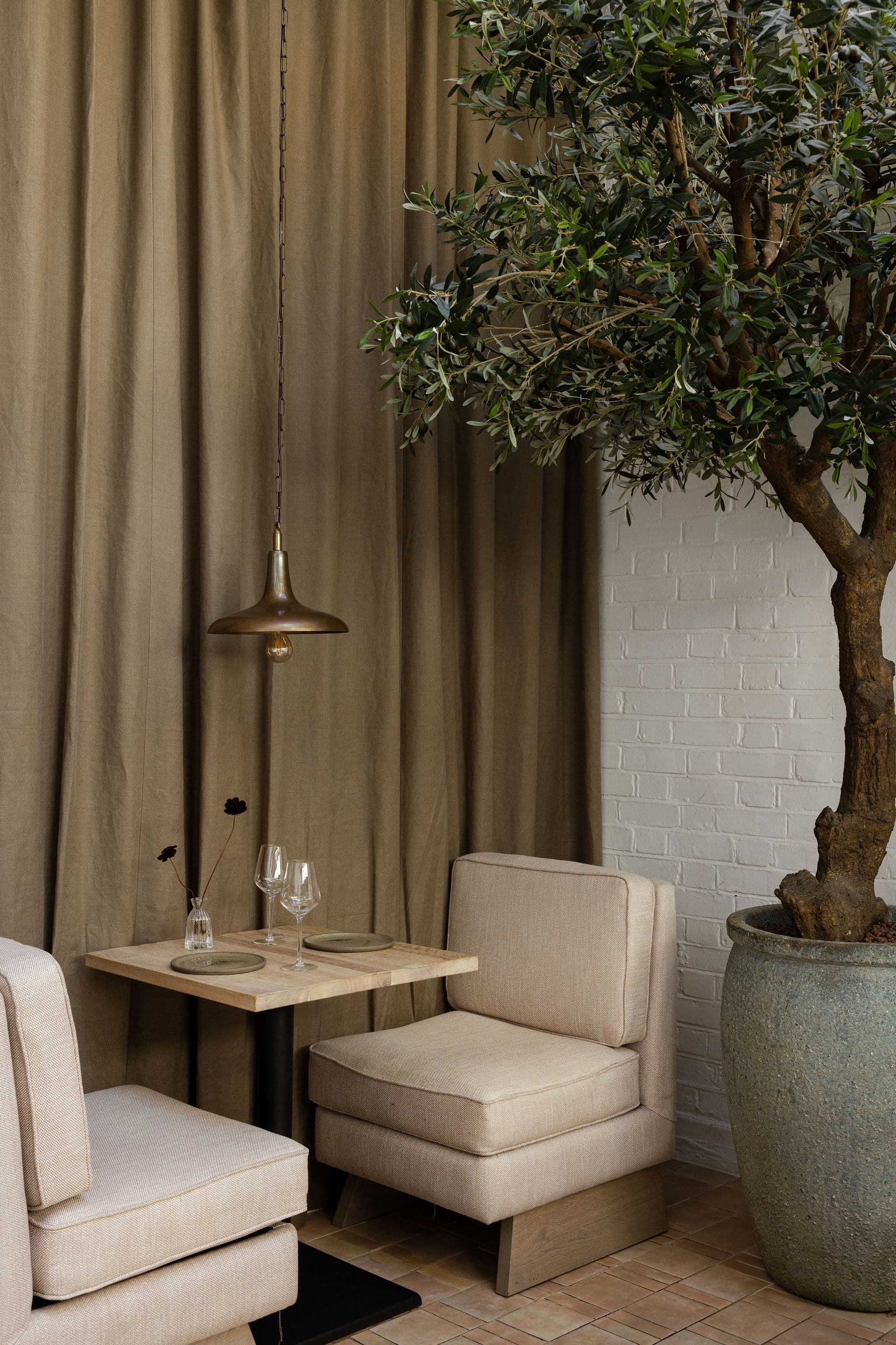 A tree and upholstered seating occupy a softly lit corner.
