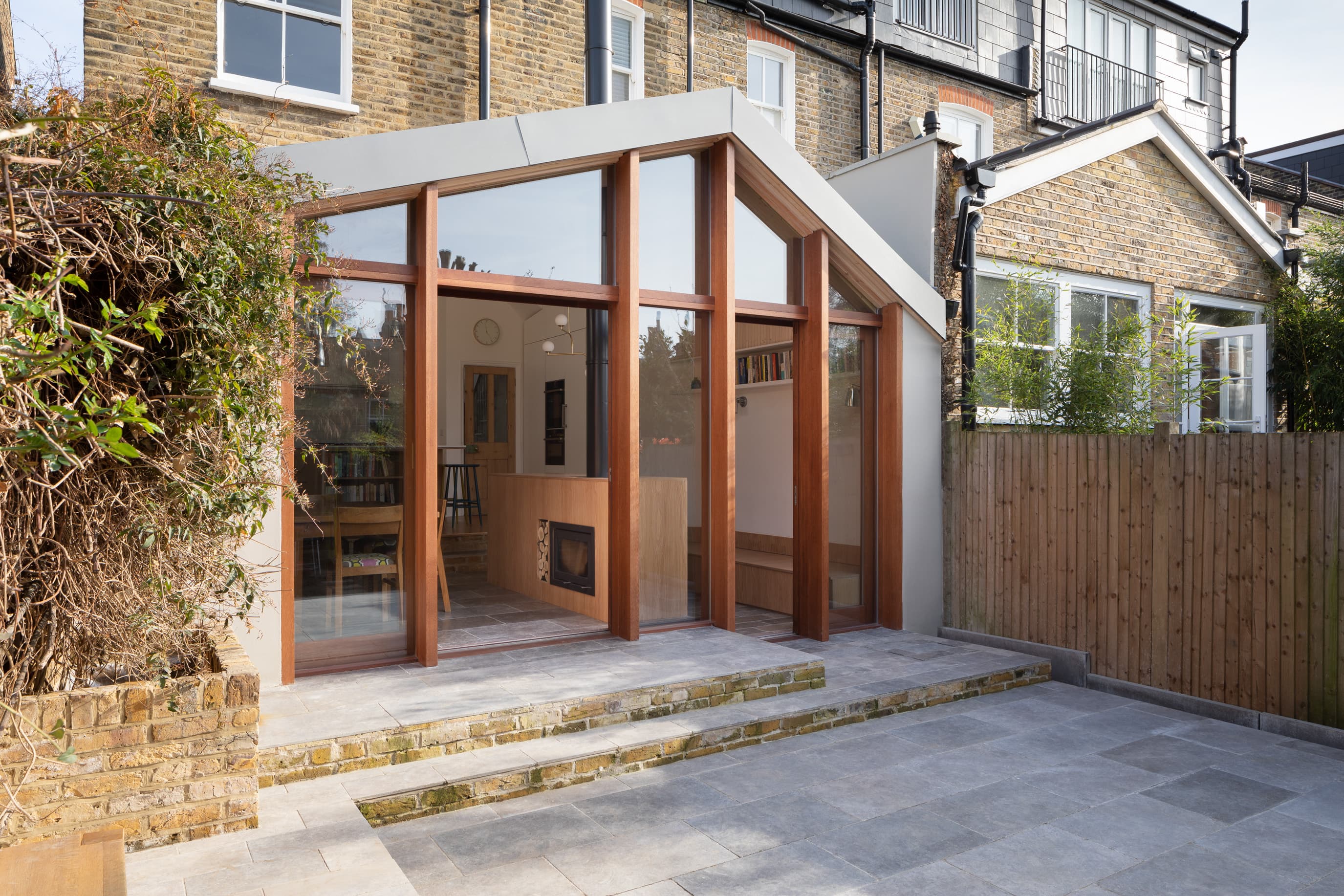The rear extension and paved terrace connect the house to the garden.