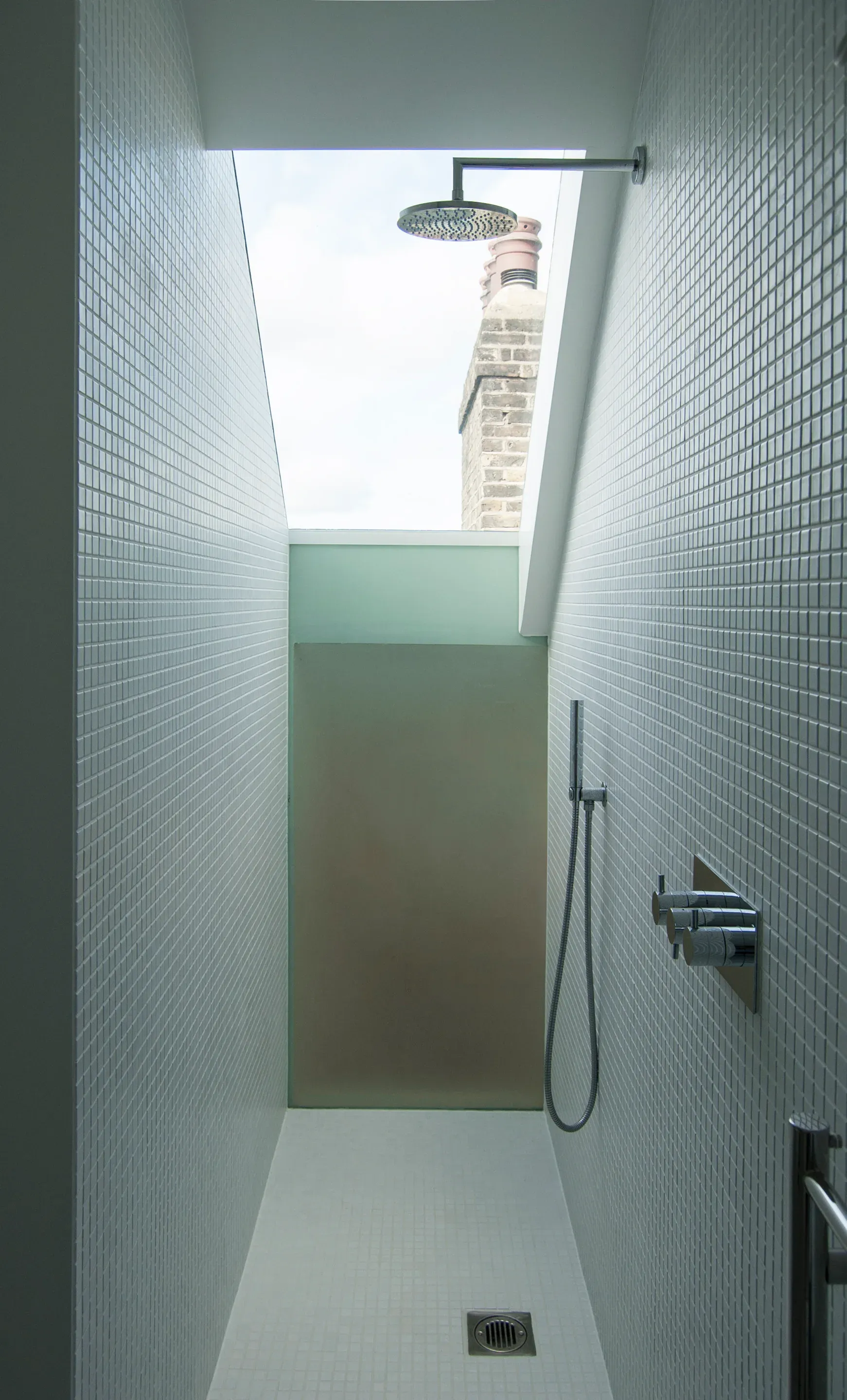 A rooflight brings daylight directly above the tiled shower.