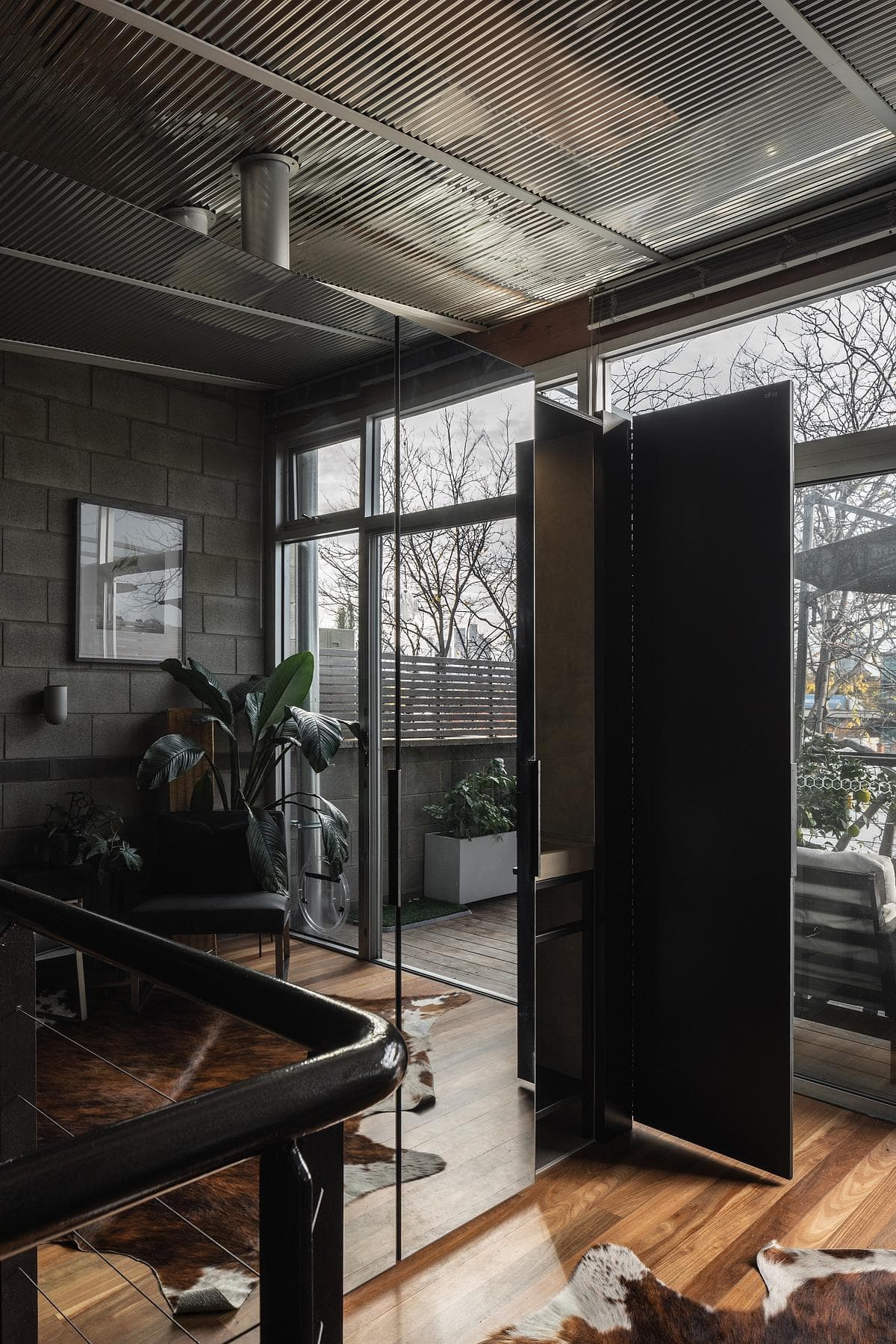 A dark mirrored enclosure sits beside the stair and glazing.