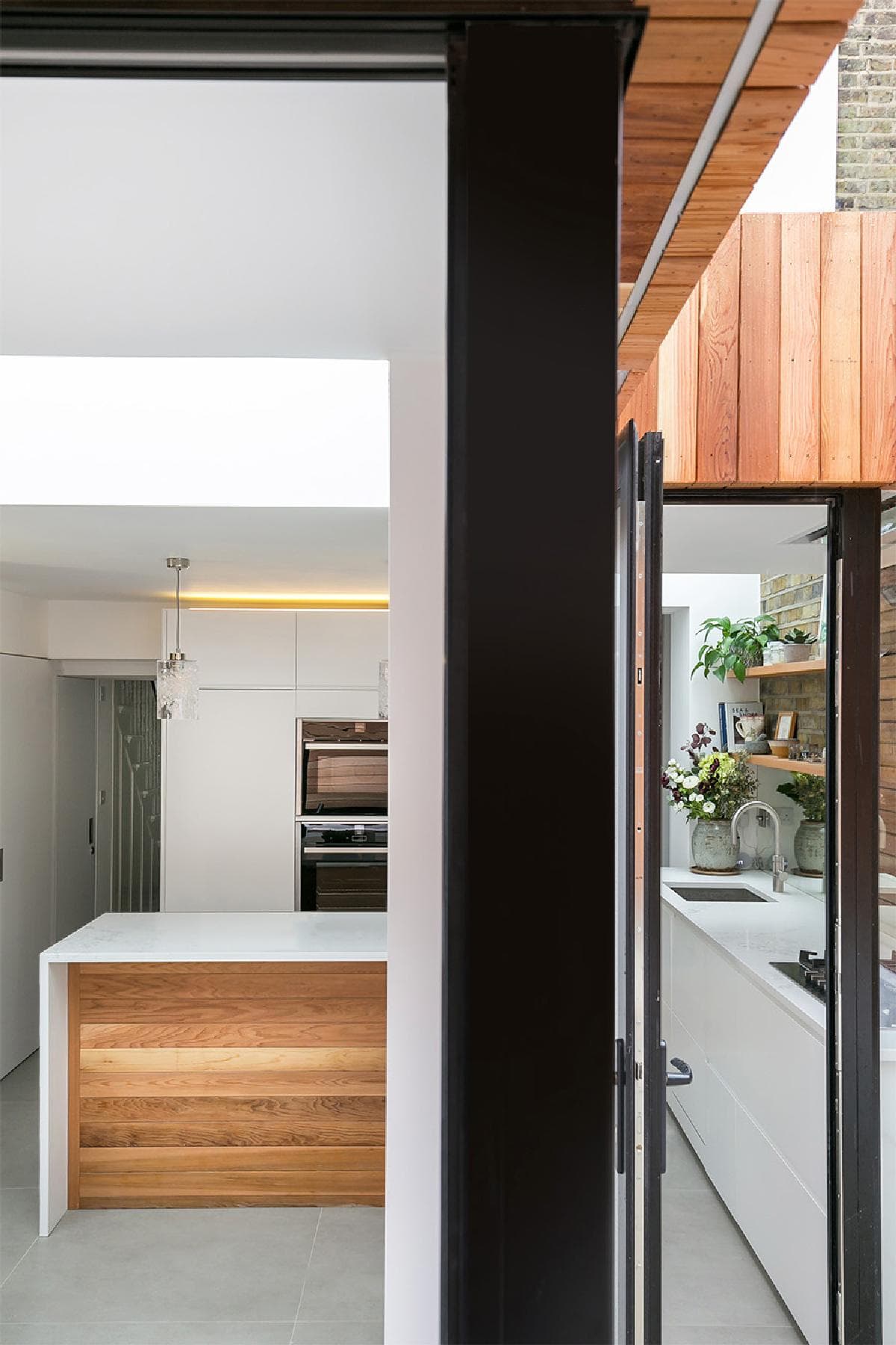 Black-framed glazing connects the kitchen with the timber-lined terrace at House in Archway.