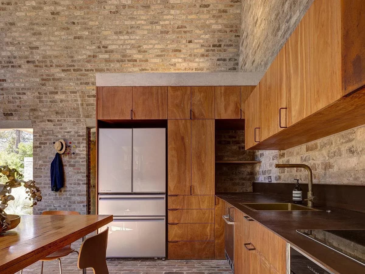 Timber cabinetry and a compact kitchen sit beneath the vaulted brick ceiling.