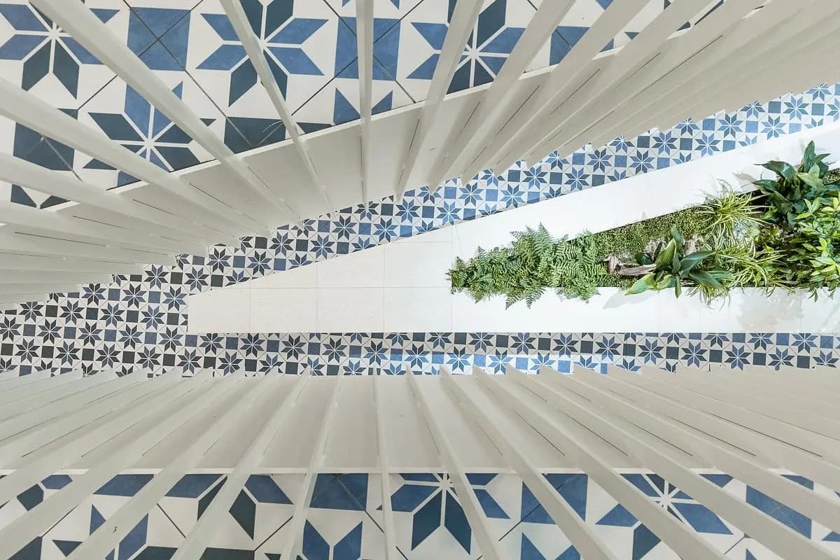 Patterned tiles and white balustrades wrap around the atrium stair.