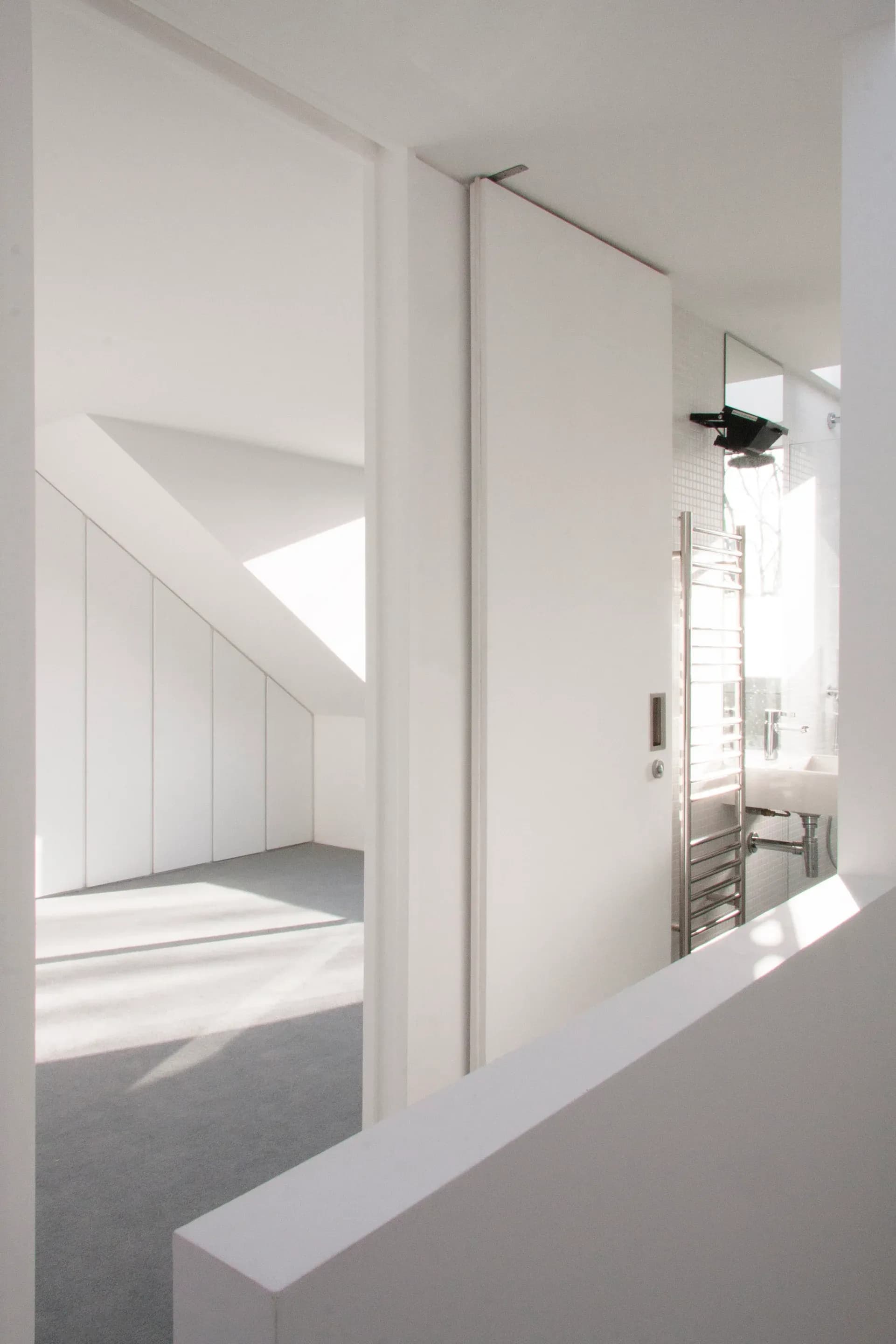 A mirror reflects the timber staircase and high-level daylight.