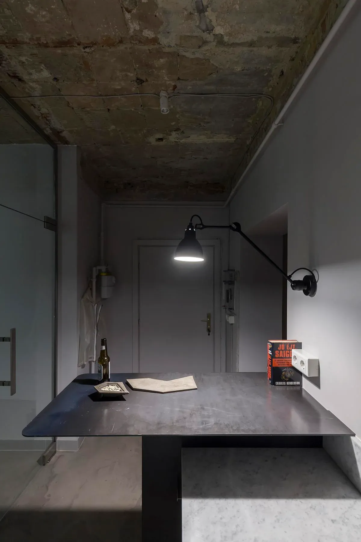 A dark table sits below the exposed ceiling and wall light.