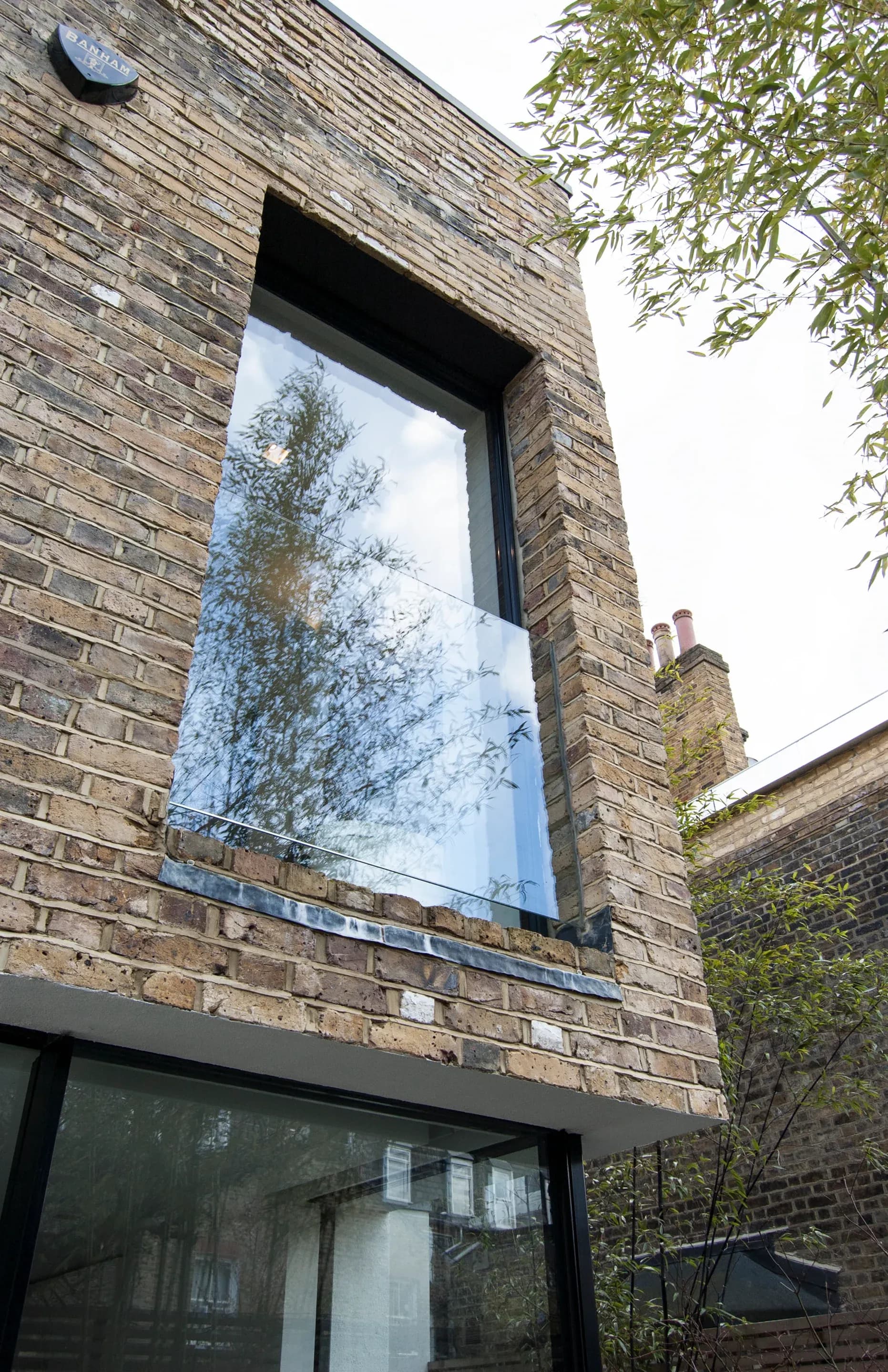 A large window cuts into the brick plane of the rear elevation.