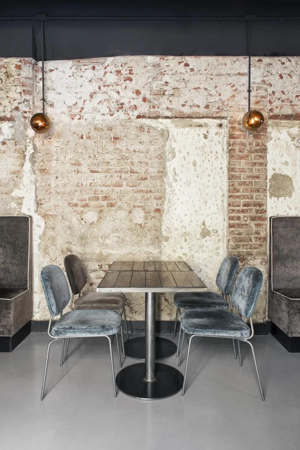 Velvet seating and metal tables sit against the exposed brickwork.