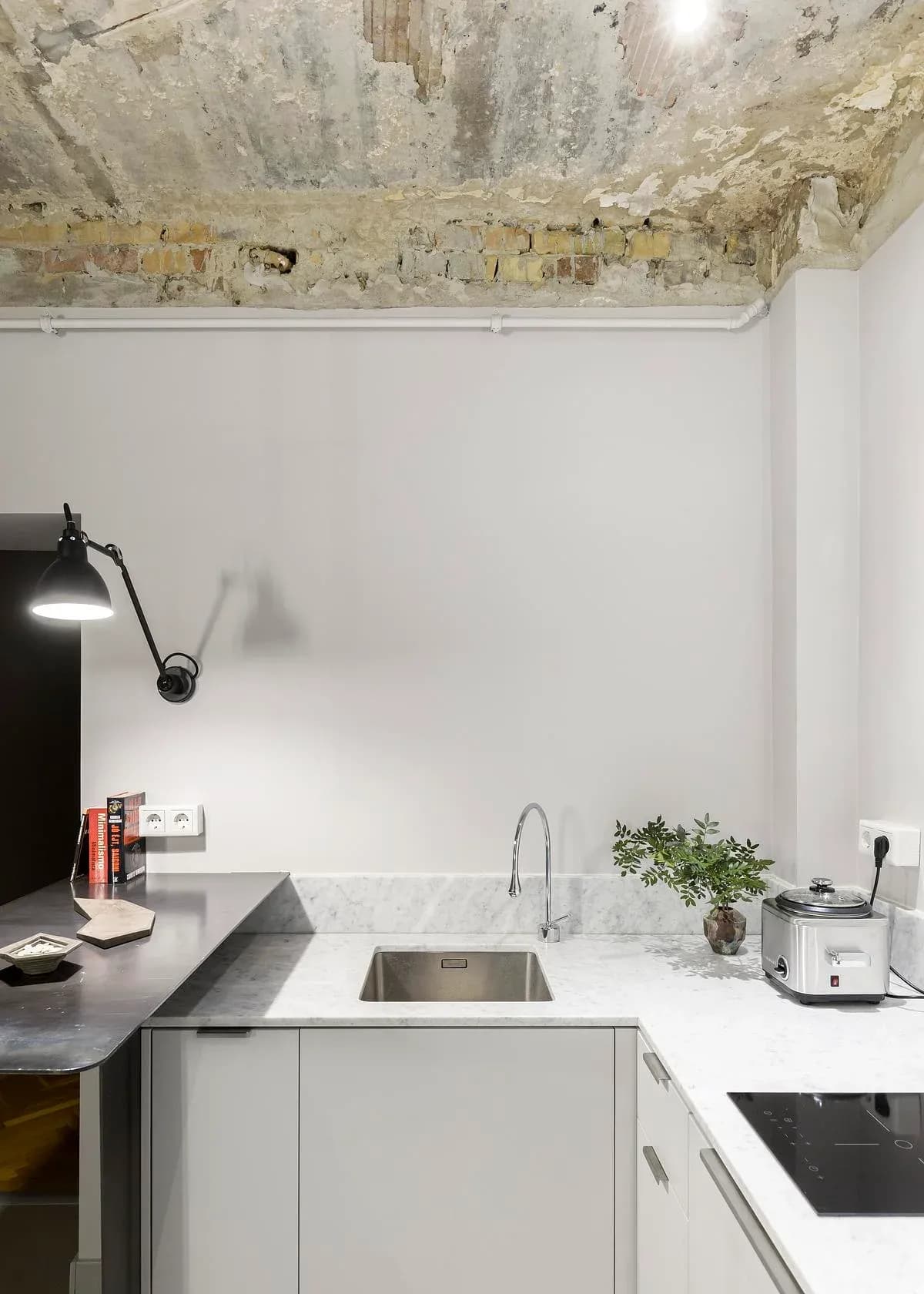 Kitchen counters meet beneath an exposed structural ceiling.