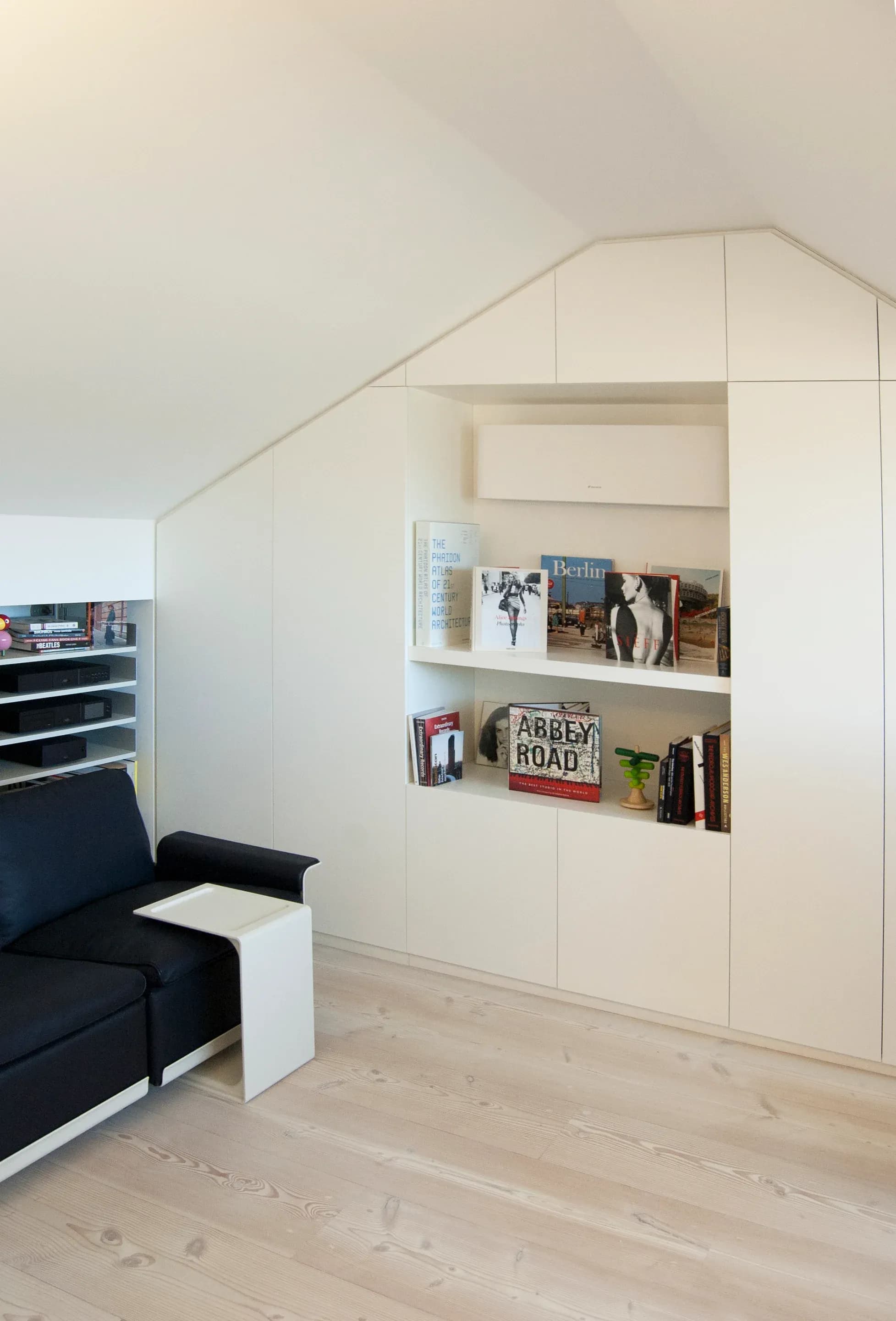 Built-in shelving follows the roof profile in an upper room.
