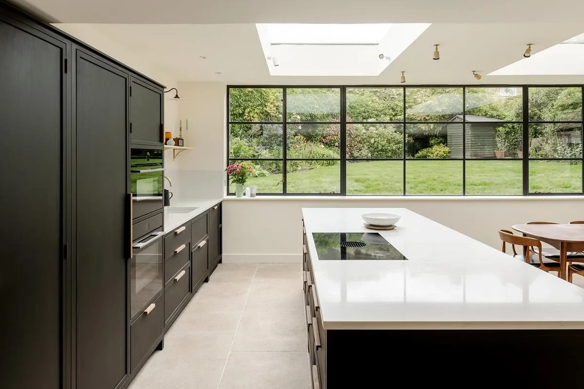 A long kitchen island runs beneath a rooflight towards the garden window.