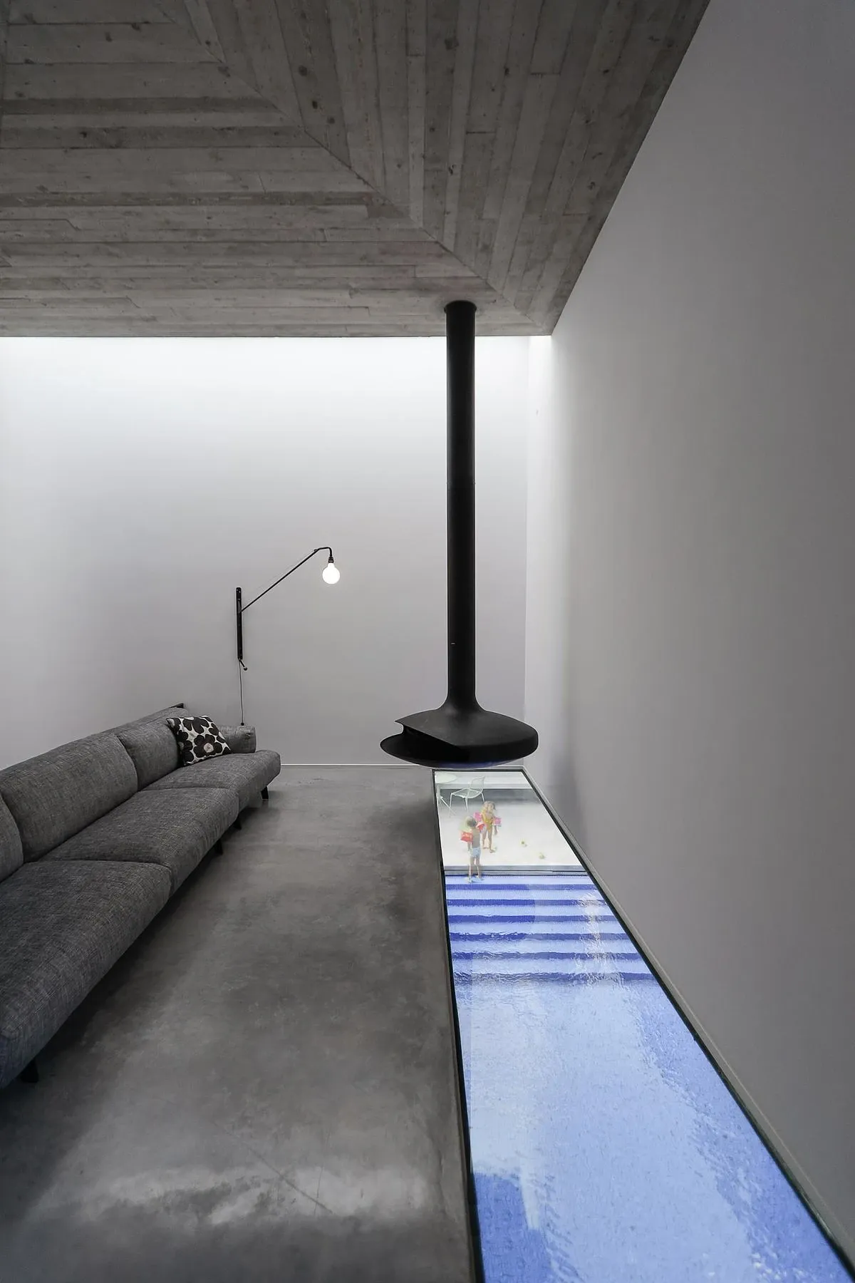A floor window beside the living-room sofa looks straight down into the pool.