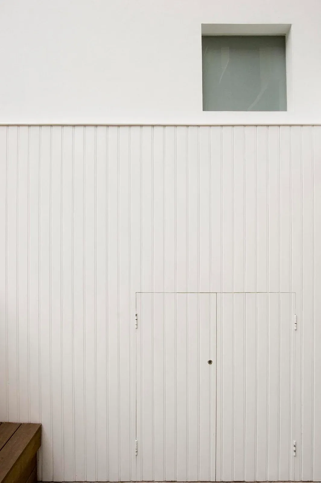 White vertical panelling encloses storage below a high window at Periscope.