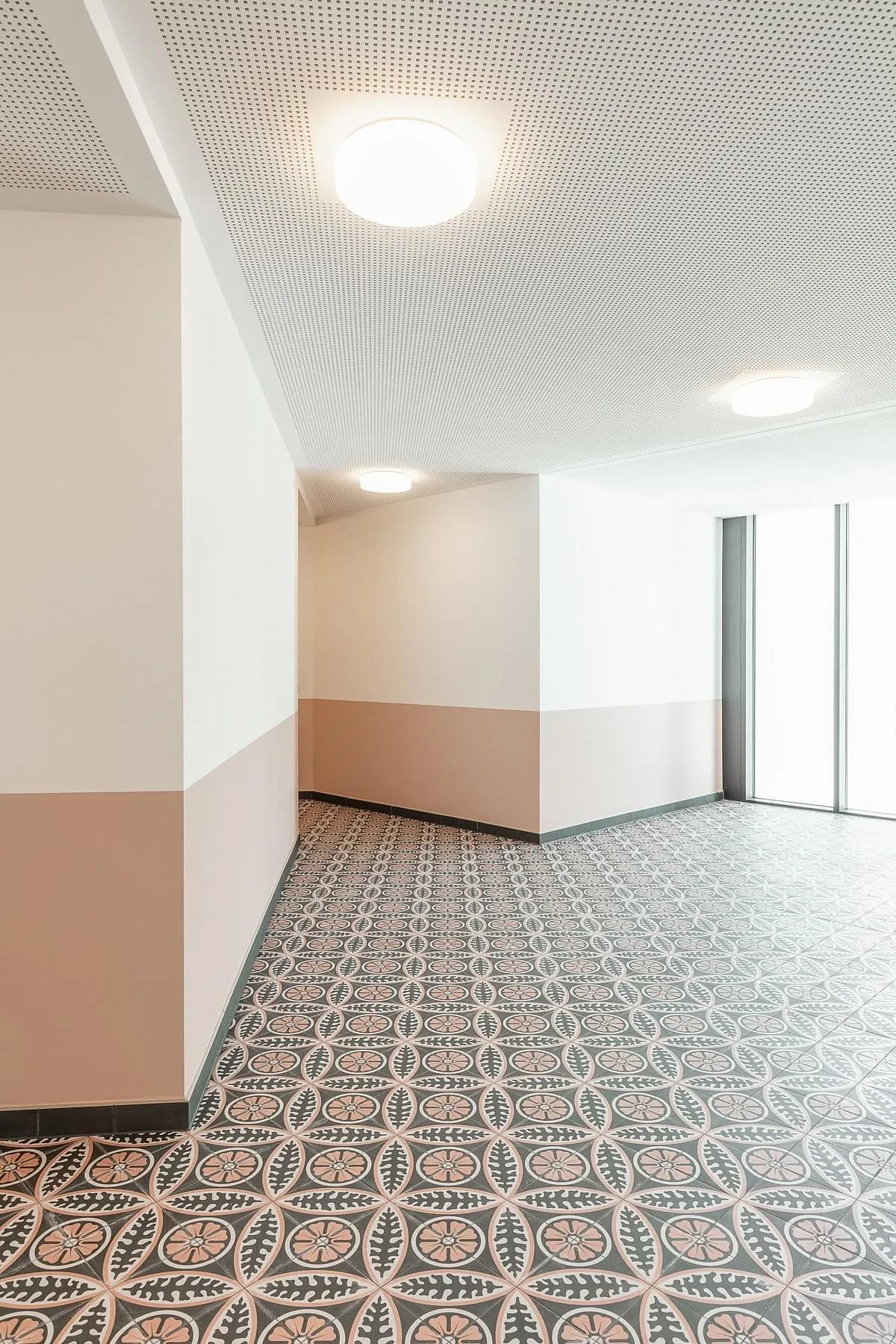 Patterned floor tiles and pink-toned walls line a landing outside the homes.