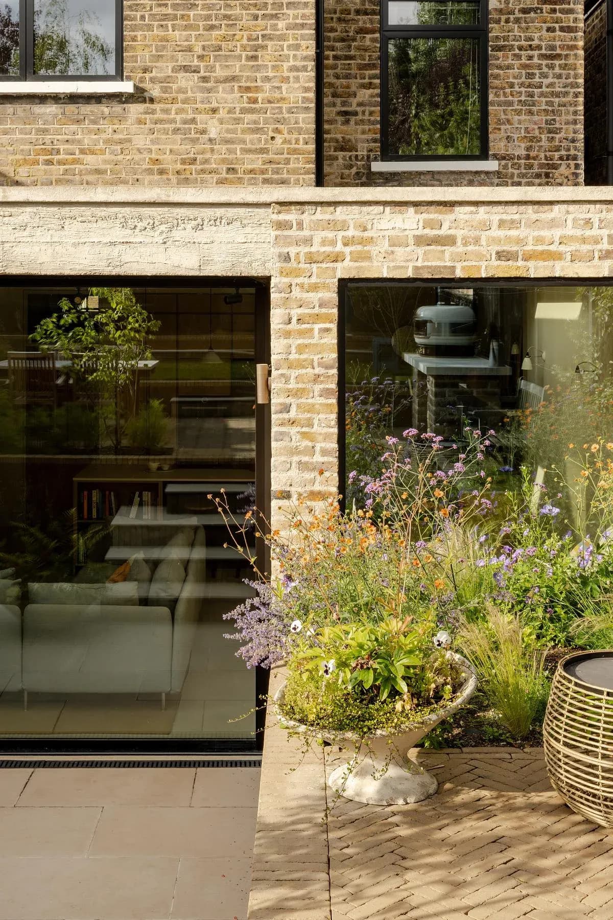 A garden-level opening connects the brick extension to the planted terrace.