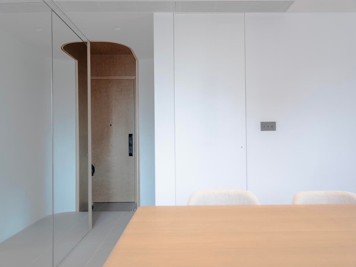 Pale cabinetry and a rounded doorway organise the dining and entrance spaces.