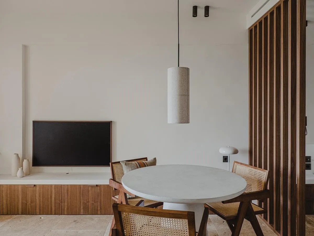 A round dining table sits beside fitted timber storage.