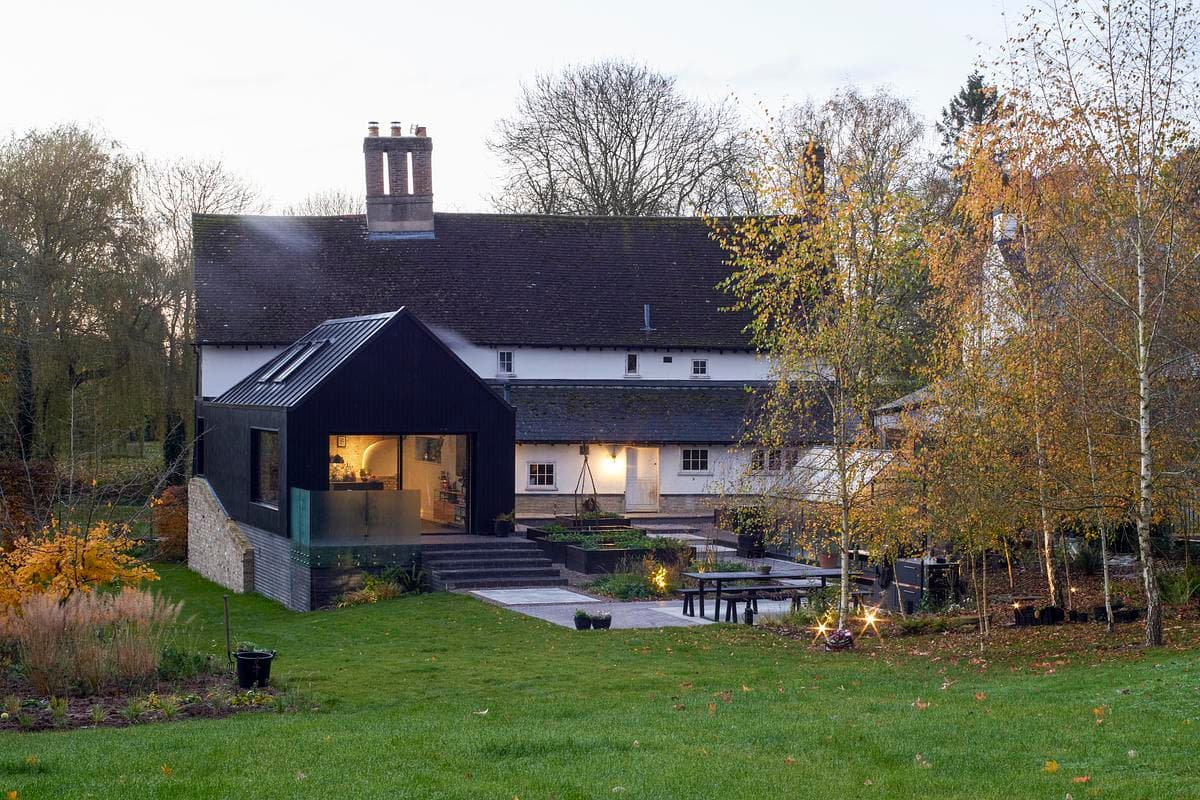 The timber and zinc addition sits beside the historic farmhouse, seen from the garden.