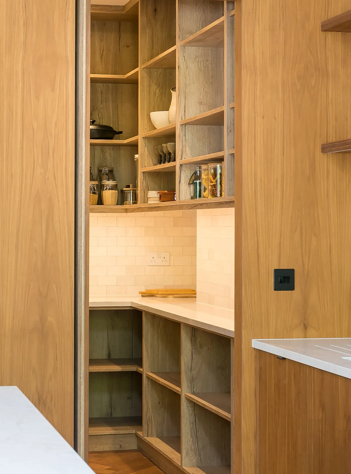 Timber-veneer joinery conceals a walk-in pantry behind the kitchen.