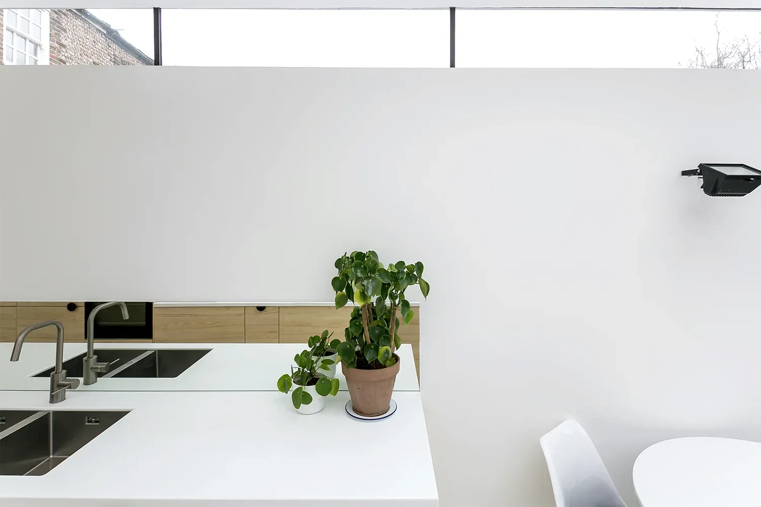 High-level glazing lights the kitchen worktop and dining corner.