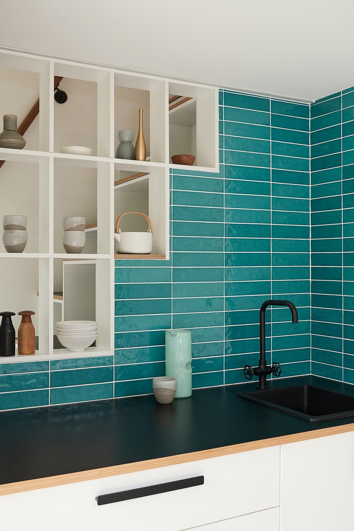 Turquoise tile follows the stair profile above the kitchenette.