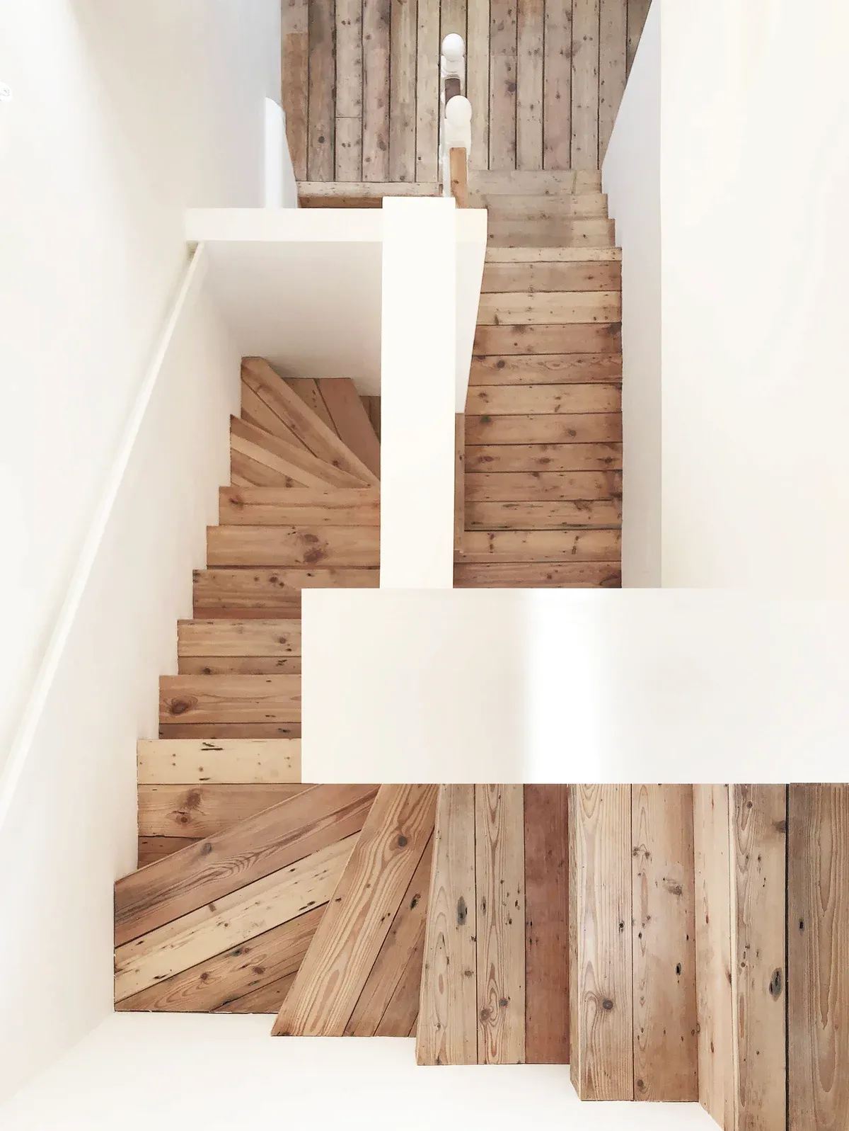 Timber stair treads and white guarding form an open sculptural composition.