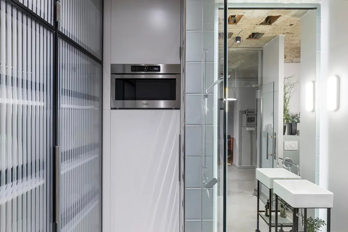 Kitchen cabinetry, mirrors and exposed ceiling structure share the compact interior.