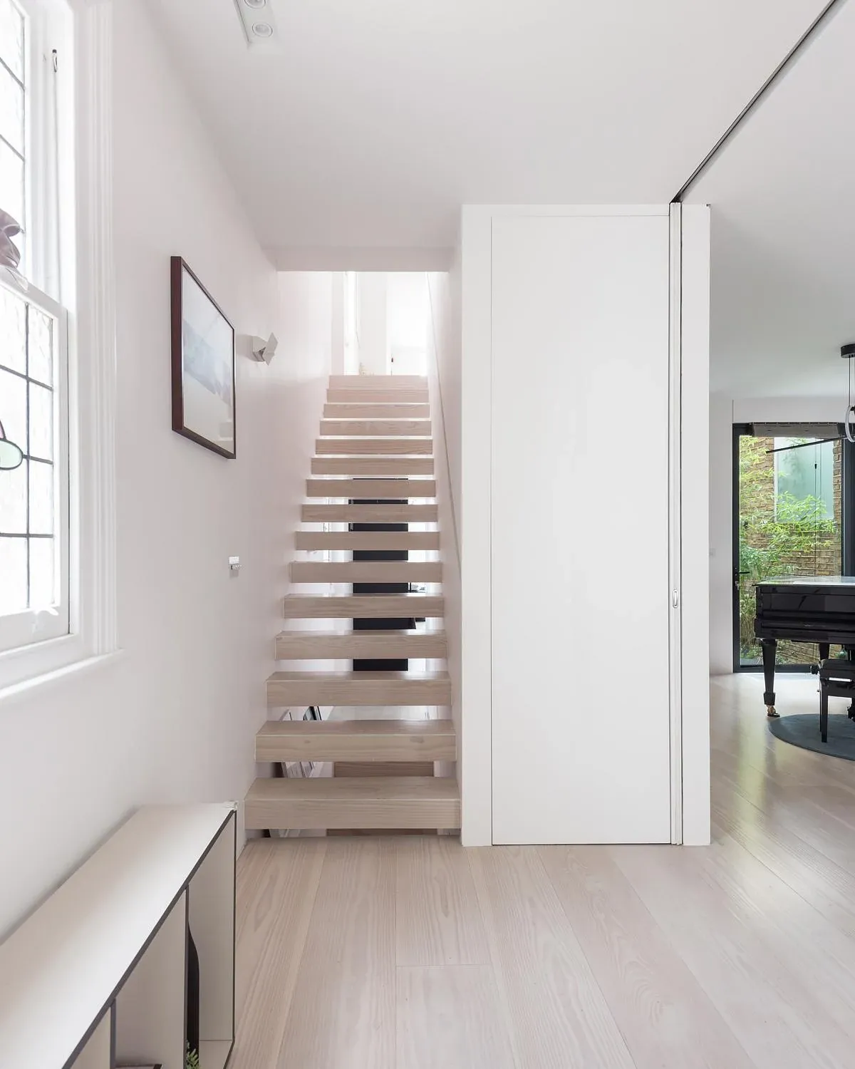 Open-riser timber stair and concealed white door in the refurbished house.