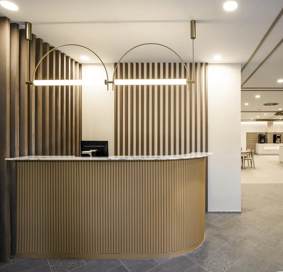 A curved timber-clad counter sits beneath arched brass light fittings.