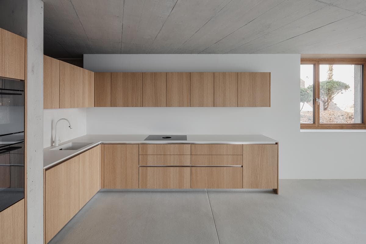 Timber cabinetry lines a kitchen with a pale worktop and island.
