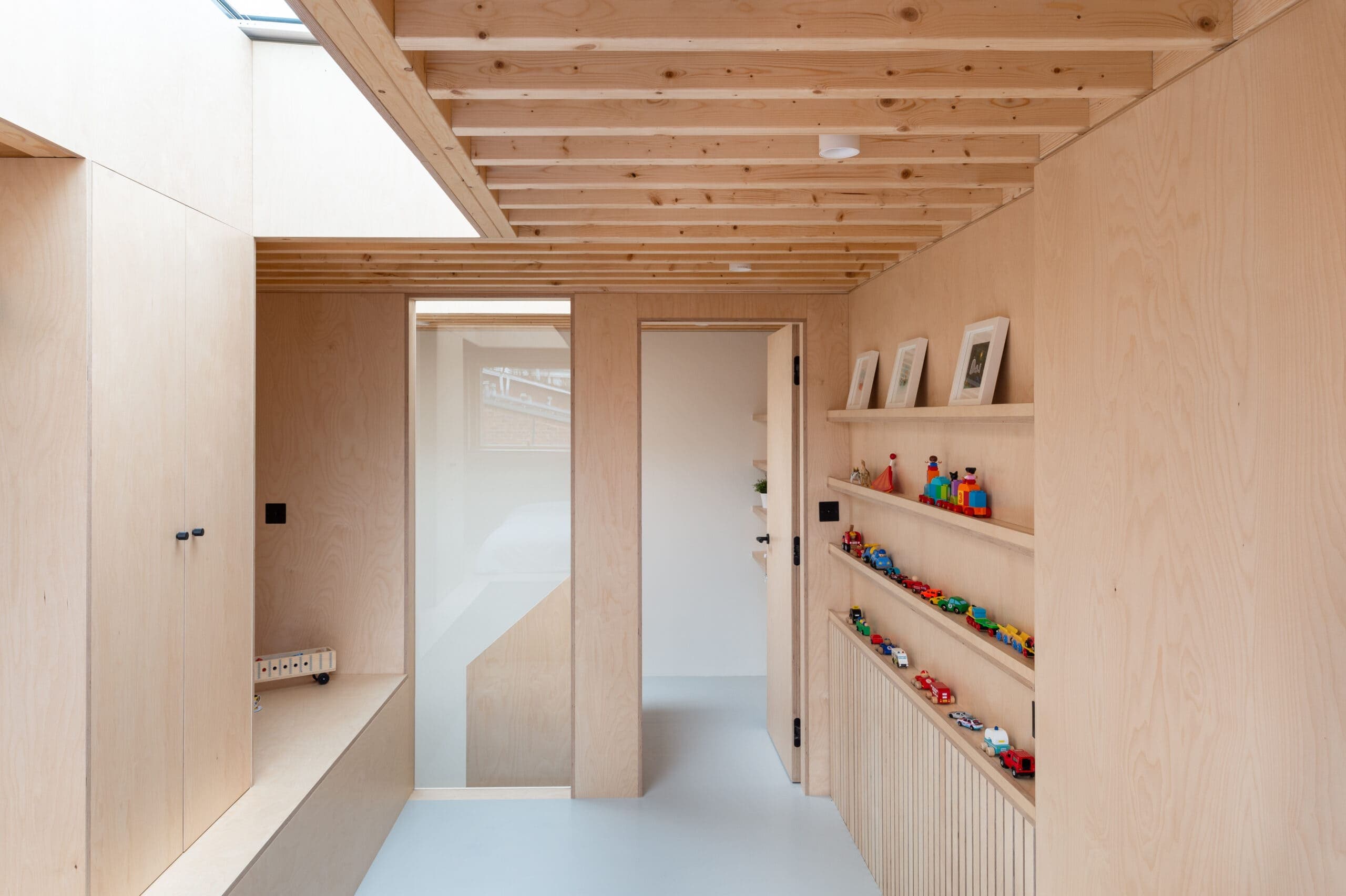 Upper room with plywood lining, shelves and a doorway.
