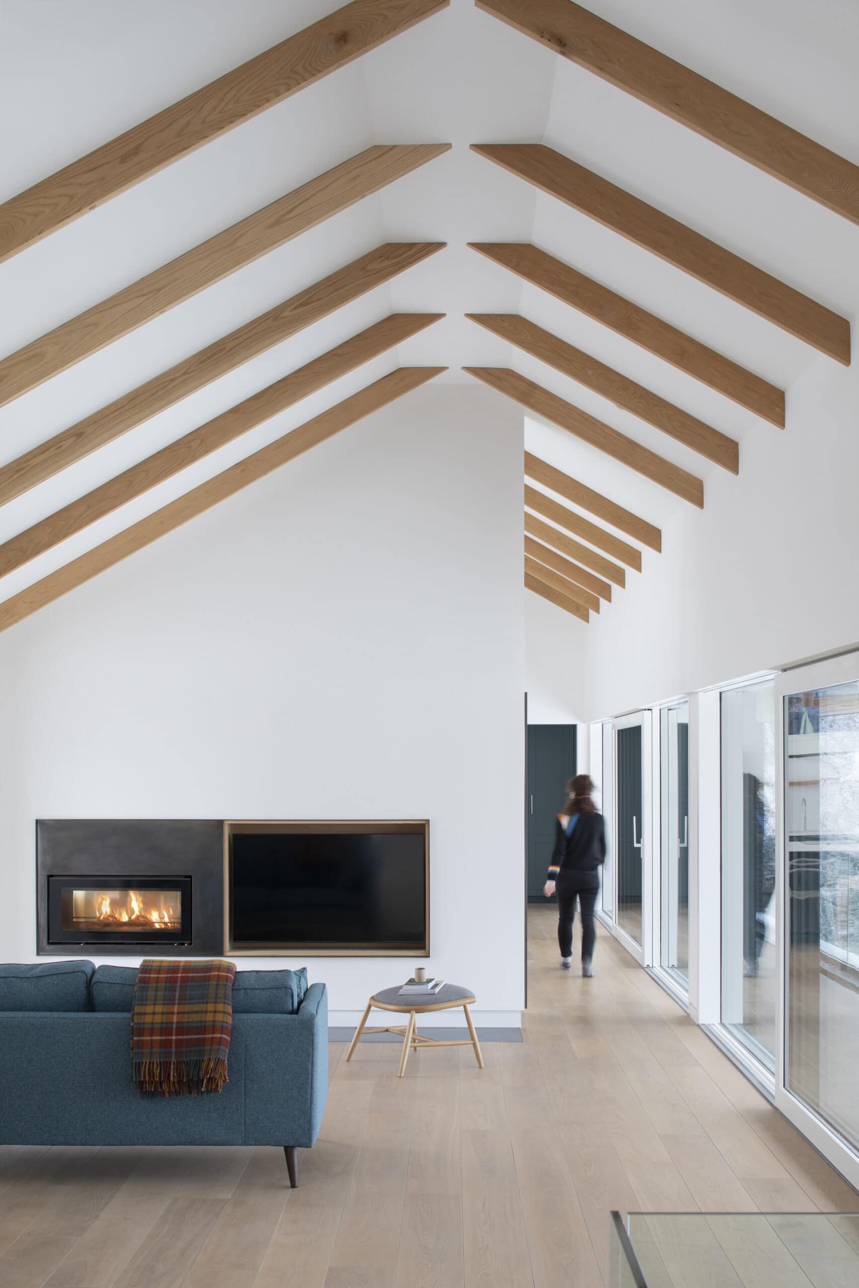 Living space with exposed pitched roof beams and a fireplace.